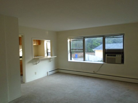 an empty living room with a large window and a kitchen